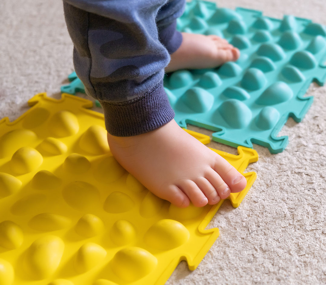 Kleine Babyfüße auf einem gerippten Teppich