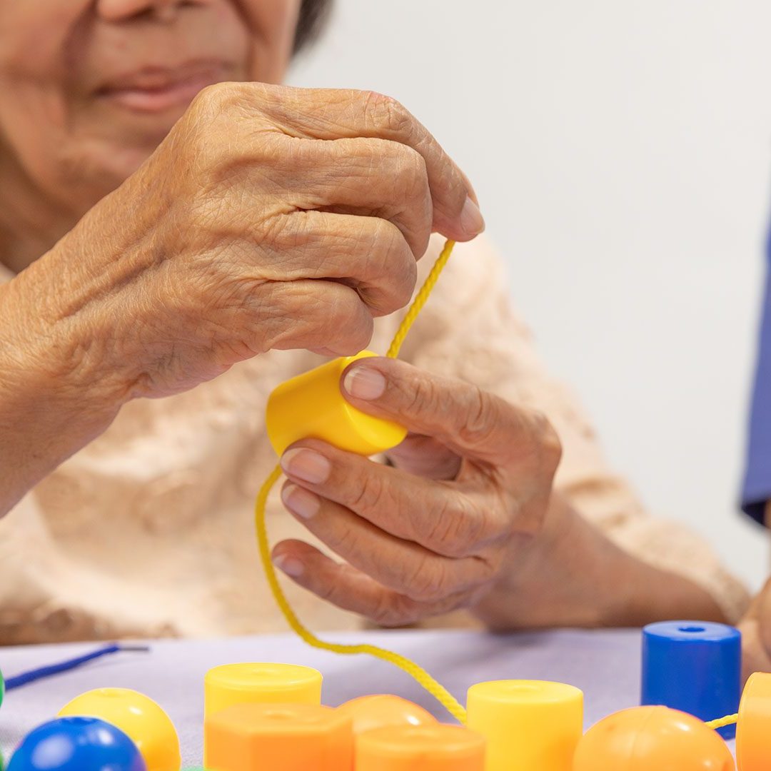 Therapeut und ältere Frau, die Perlenspiel zur Demenzprävention spielen